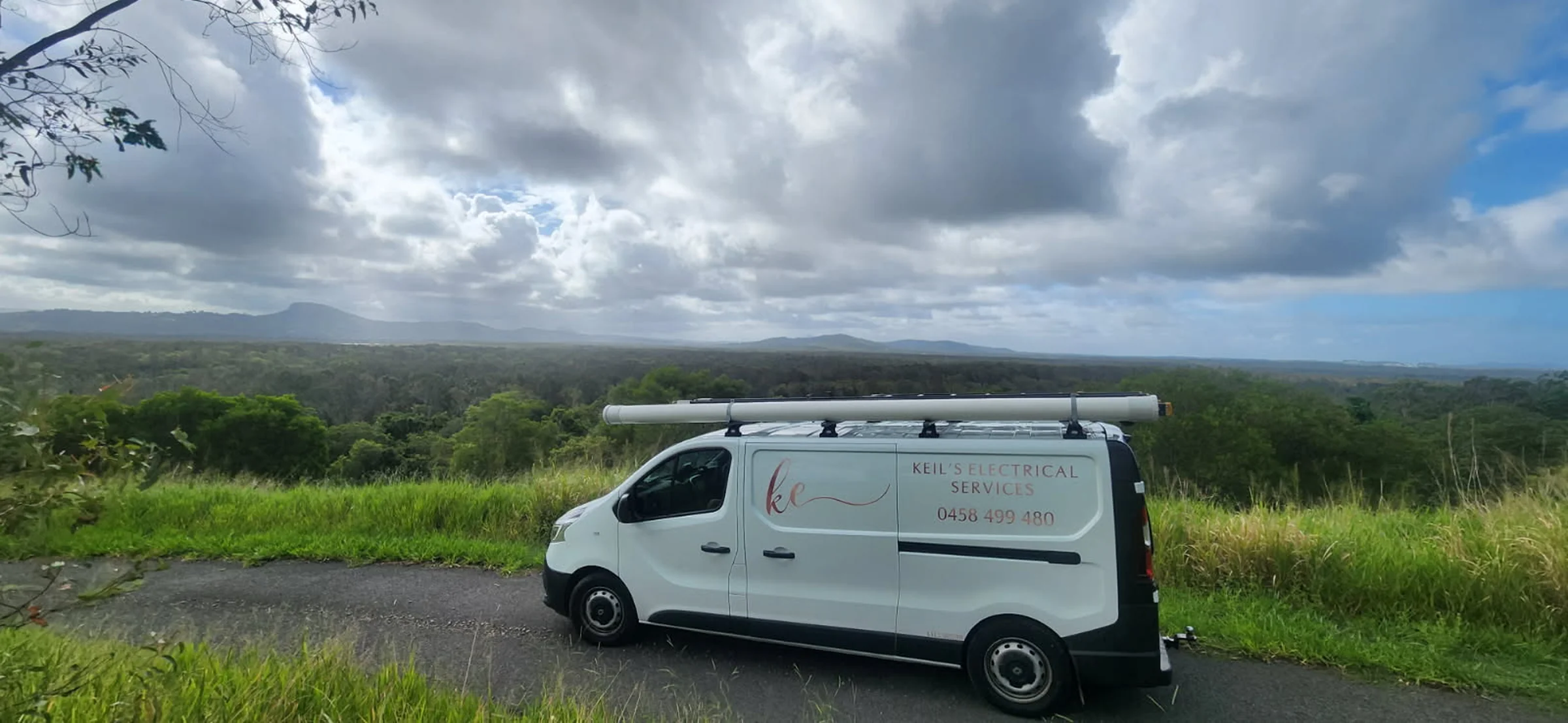 Keil's Electrical Services van, white with the rose-gold ke logo, parked at a lookout over the bush