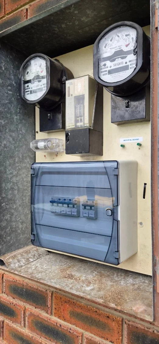 Switchboard upgrade with new circuit breakers in a clear-cover enclosure below two electricity meters
